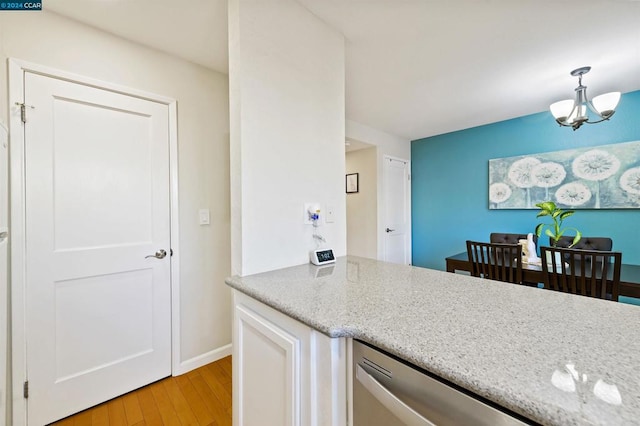 kitchen featuring light stone counters, pendant lighting, a chandelier, and light hardwood / wood-style floors