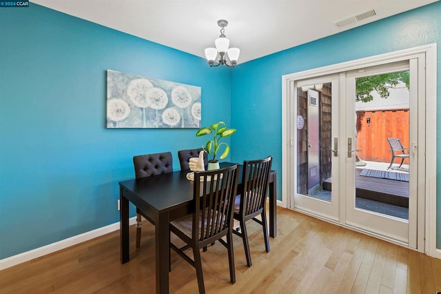 dining area with light hardwood / wood-style flooring, french doors, and a notable chandelier