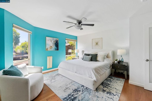 bedroom featuring ceiling fan, hardwood / wood-style floors, and multiple windows