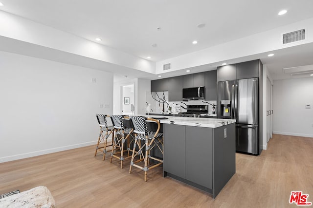 kitchen featuring appliances with stainless steel finishes, light hardwood / wood-style floors, a kitchen breakfast bar, and kitchen peninsula