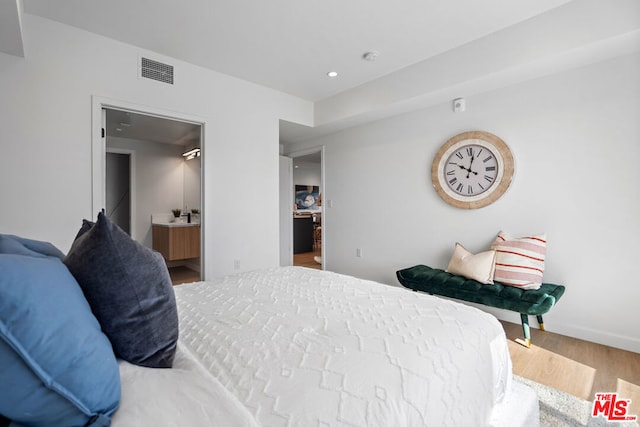 bedroom featuring wood-type flooring and connected bathroom