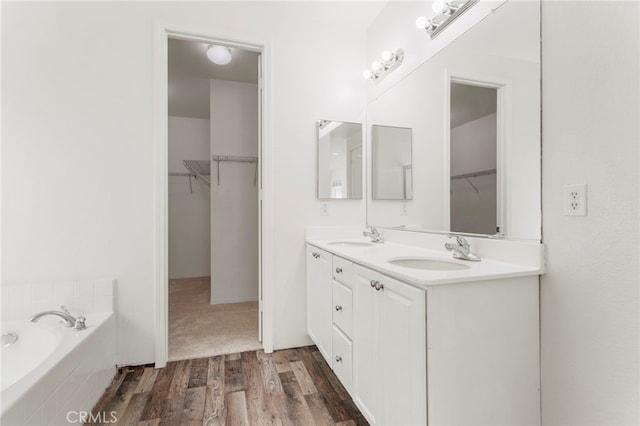 bathroom featuring tiled bath, hardwood / wood-style floors, and vanity