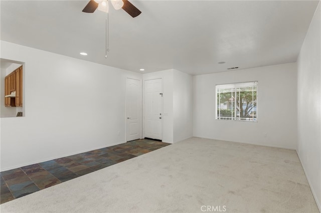 spare room featuring dark colored carpet and ceiling fan