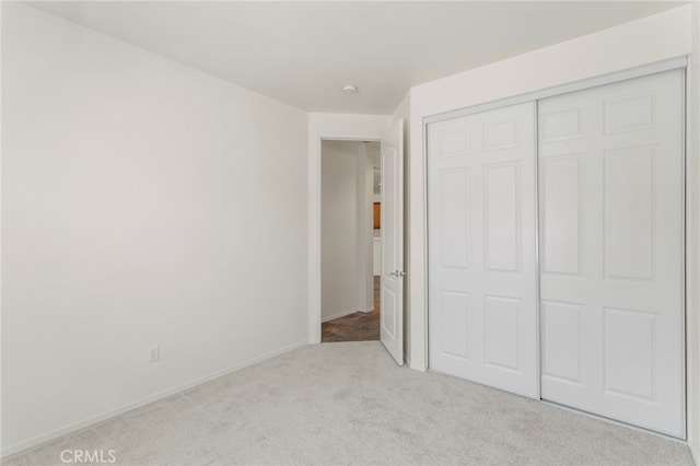 unfurnished bedroom with light carpet and a closet