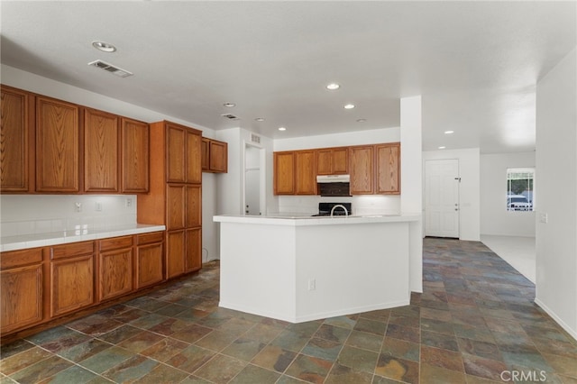 kitchen with stove and a center island with sink