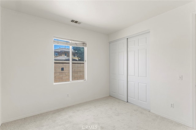 unfurnished bedroom with light colored carpet and a closet