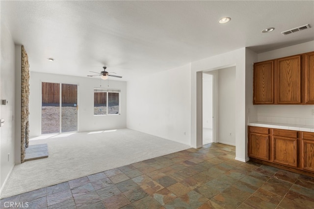 unfurnished living room with ceiling fan and dark carpet