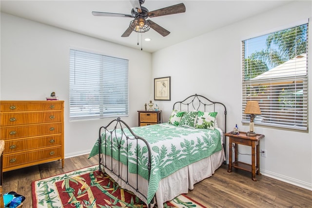 bedroom featuring ceiling fan, multiple windows, and dark hardwood / wood-style flooring