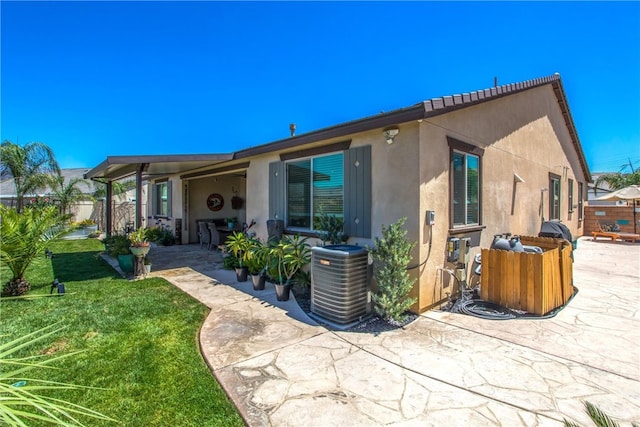 back of house featuring central AC, a yard, and a patio area