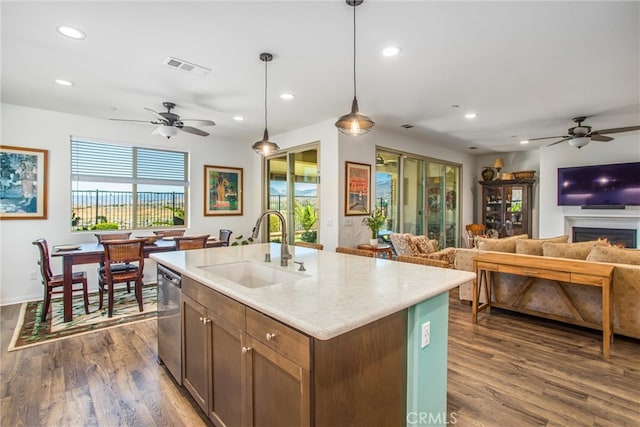 kitchen featuring decorative light fixtures, sink, plenty of natural light, and an island with sink