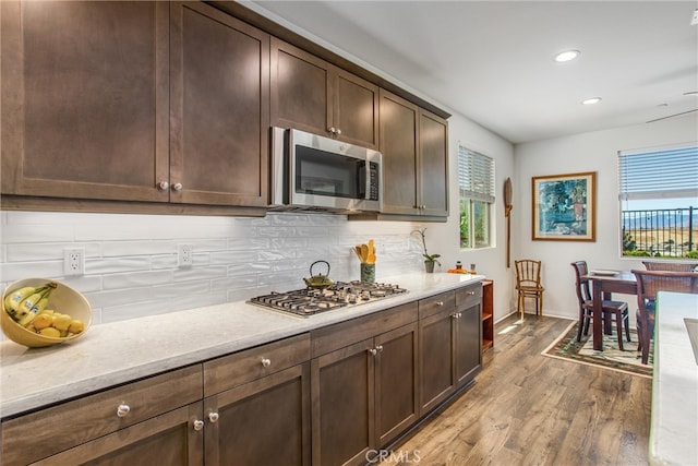 kitchen featuring dark brown cabinets, stainless steel appliances, light hardwood / wood-style floors, and tasteful backsplash