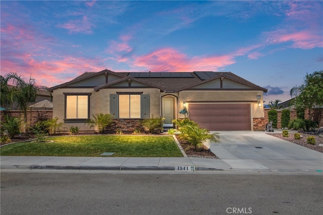 view of front of home featuring solar panels, a garage, and a lawn