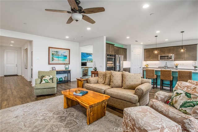 living room featuring ceiling fan, hardwood / wood-style flooring, and sink