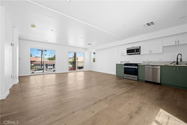 kitchen featuring sink, stainless steel appliances, green cabinets, white cabinets, and light wood-type flooring