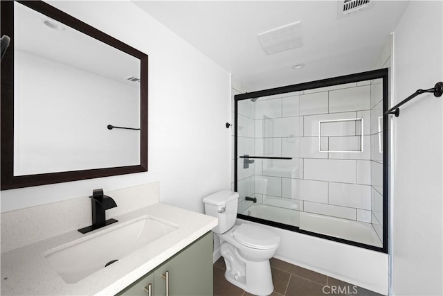 full bathroom with tile patterned floors, vanity, bath / shower combo with glass door, and toilet