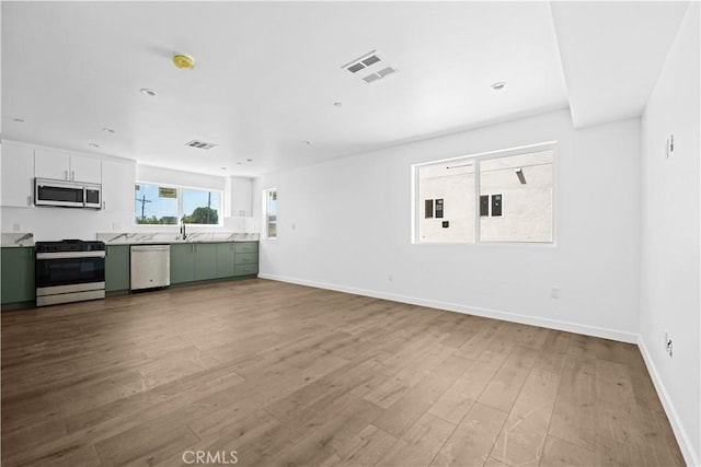 unfurnished living room featuring sink and light hardwood / wood-style flooring