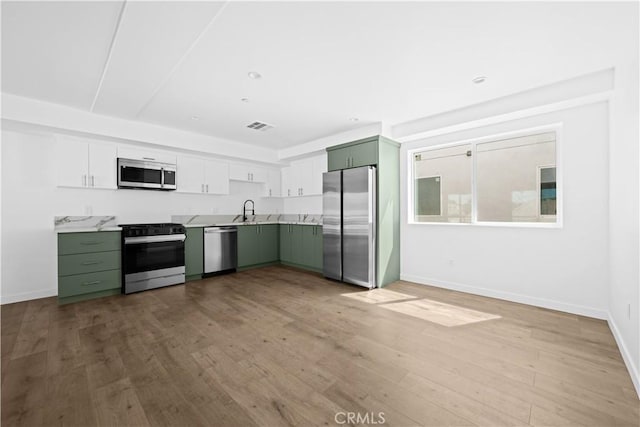 kitchen with white cabinets, stainless steel appliances, and green cabinetry