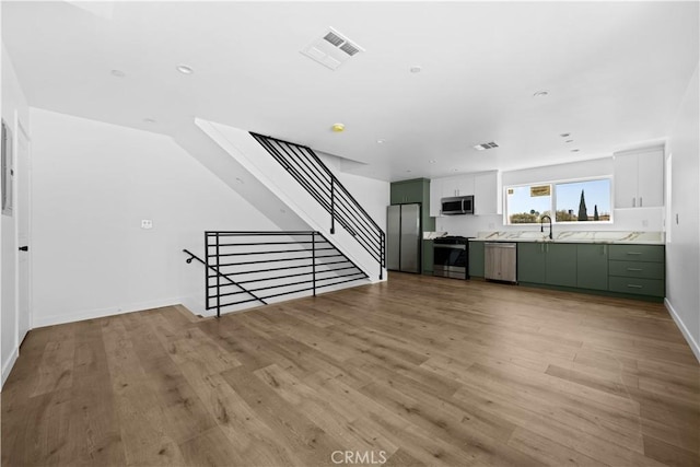 unfurnished living room with sink and light hardwood / wood-style flooring