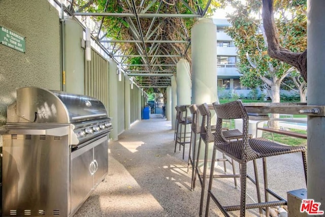 view of patio / terrace featuring exterior bar, area for grilling, and a grill