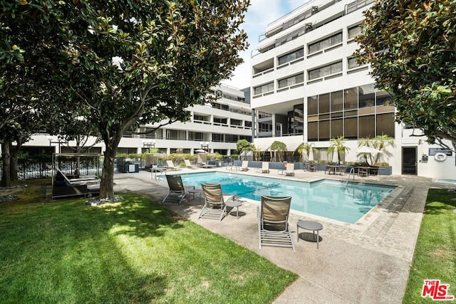 view of pool featuring a lawn, a sunroom, and a patio area