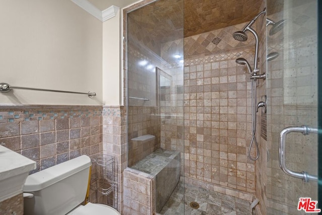 bathroom featuring vanity, ornamental molding, tile walls, toilet, and a shower with door