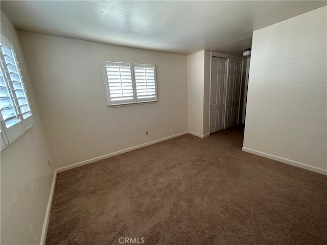 spare room with dark colored carpet