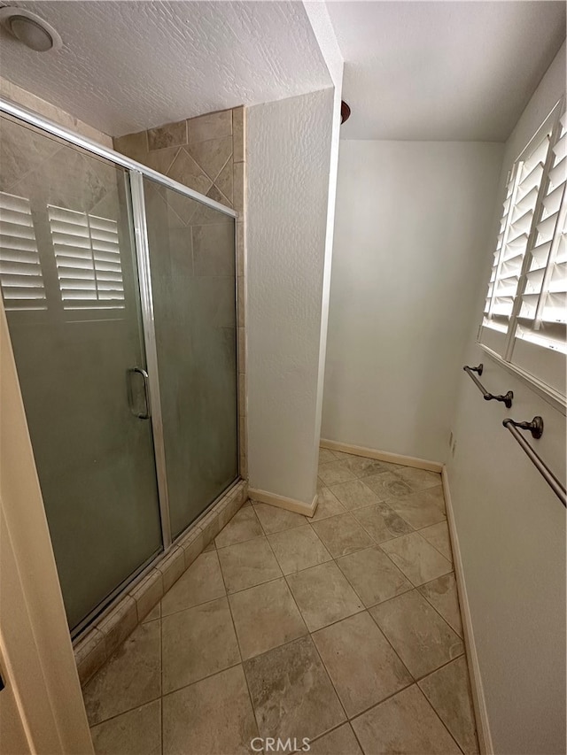 bathroom featuring tile patterned flooring, a textured ceiling, and a shower with door