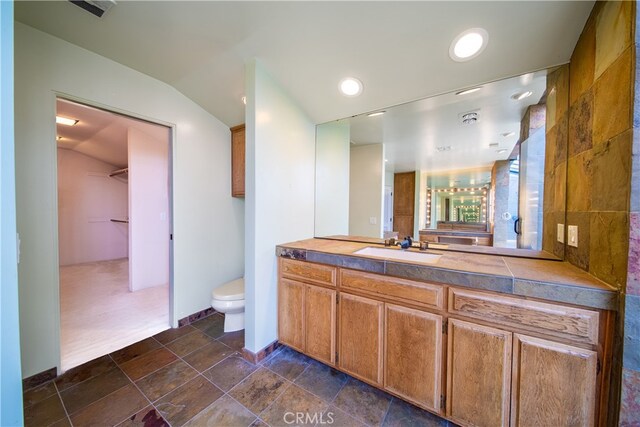 bathroom with vanity, lofted ceiling, and toilet