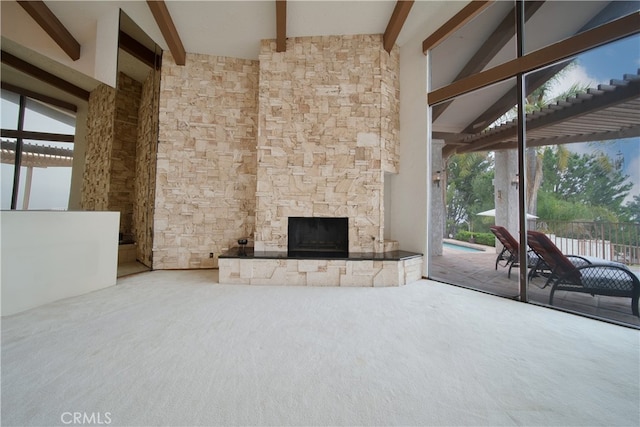 unfurnished living room with plenty of natural light, beam ceiling, a fireplace, and carpet flooring