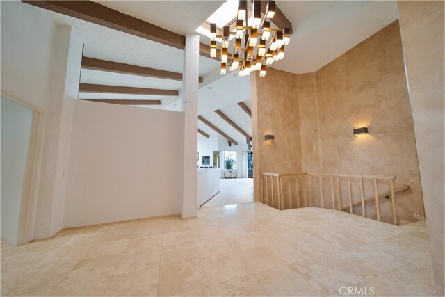 empty room featuring a notable chandelier, beamed ceiling, and high vaulted ceiling