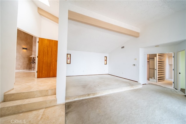 empty room featuring a textured ceiling, vaulted ceiling with beams, and carpet flooring