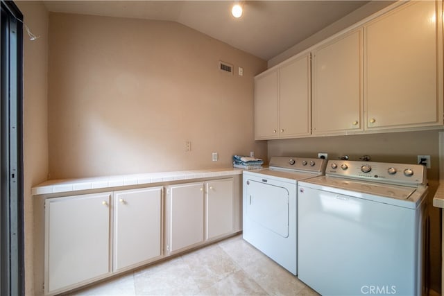 clothes washing area featuring separate washer and dryer and cabinets