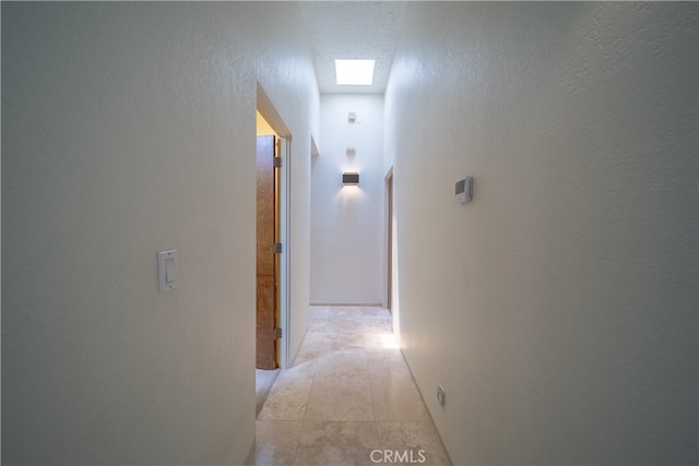 hallway with a skylight and a textured ceiling