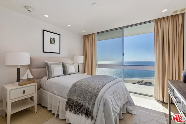 bedroom with floor to ceiling windows, access to exterior, and a water view