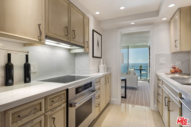 kitchen with light stone counters, sink, light tile patterned floors, backsplash, and stainless steel appliances