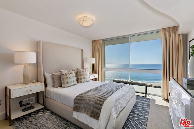 carpeted bedroom with a view of the beach, a water view, and access to exterior