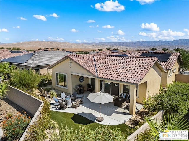 back of house featuring a patio area, a mountain view, and solar panels