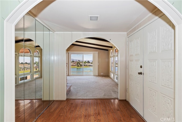 foyer entrance with lofted ceiling, ornamental molding, a water view, and dark wood-type flooring