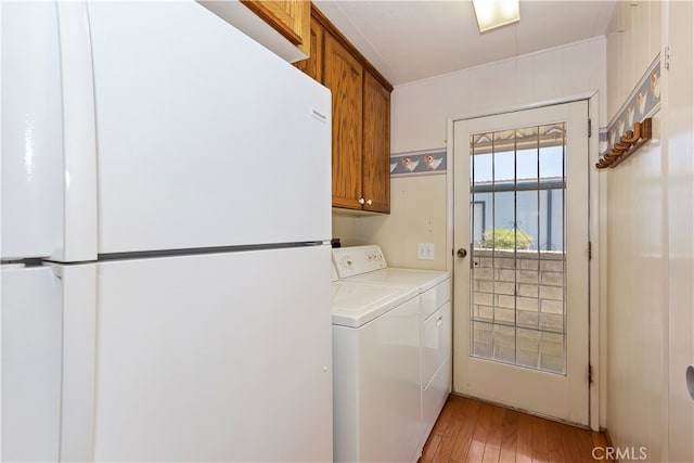 laundry area featuring light wood-type flooring, washer and dryer, and cabinets