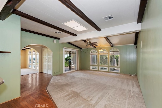 spare room featuring ceiling fan, lofted ceiling with beams, wood-type flooring, and a healthy amount of sunlight