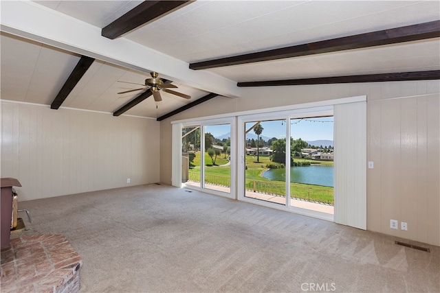 unfurnished living room featuring a water view, ceiling fan, and wood walls