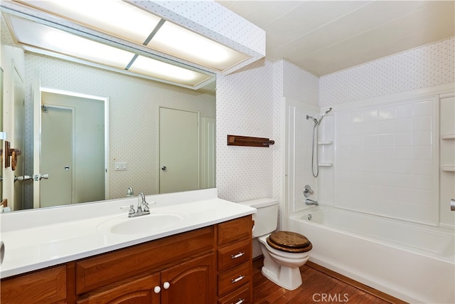 full bathroom featuring washtub / shower combination, hardwood / wood-style flooring, vanity, and toilet