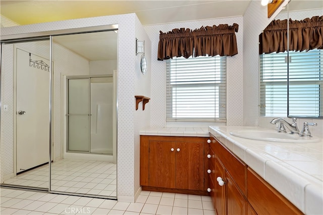 bathroom with a shower with door, vanity, tile patterned floors, and a wealth of natural light