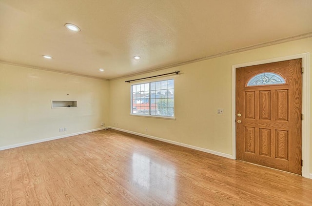 foyer entrance with light wood-type flooring and ornamental molding