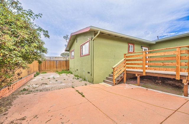 view of side of property featuring a wooden deck and a patio