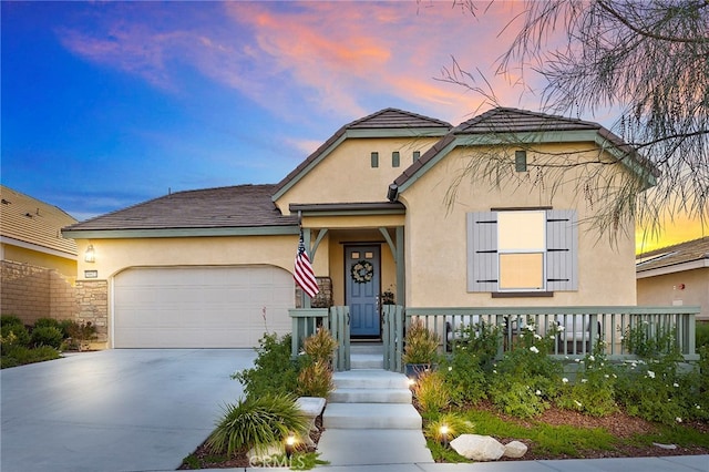 view of front of home featuring driveway, an attached garage, and stucco siding