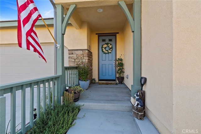 property entrance featuring an attached garage, stone siding, and stucco siding