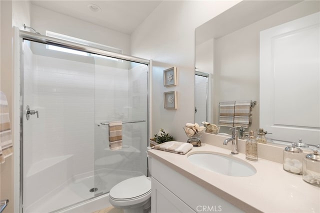 bathroom featuring a shower with door, vanity, and toilet