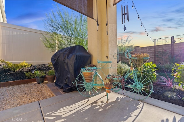 patio terrace at dusk with fence and area for grilling