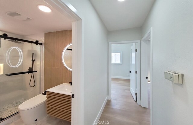 bathroom featuring baseboard heating, a shower with door, wood-type flooring, and toilet